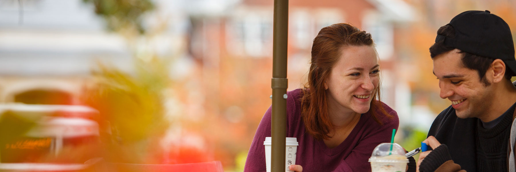 Two students laugh as they sit and drink their coffee.